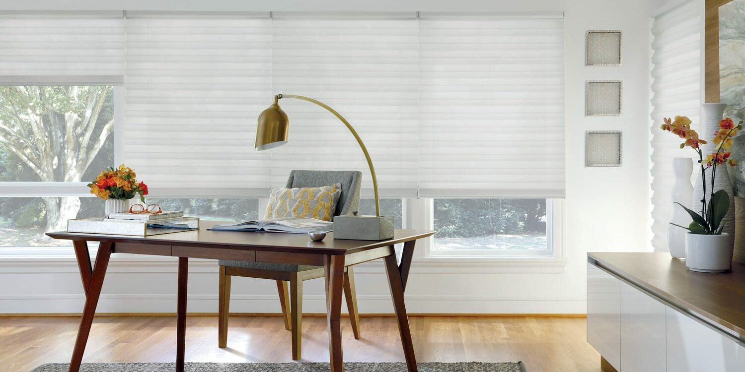home office with wide windows covered with white roman shades