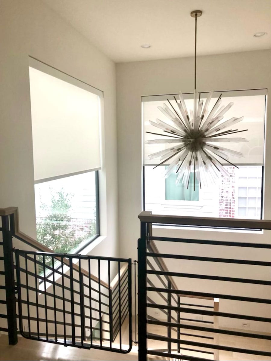 staircase in Friendswood TX with modern chandelier and roller shades