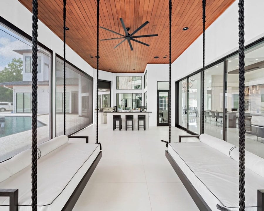 neutral sunroom with white hanging couches large windows grey closed blinds