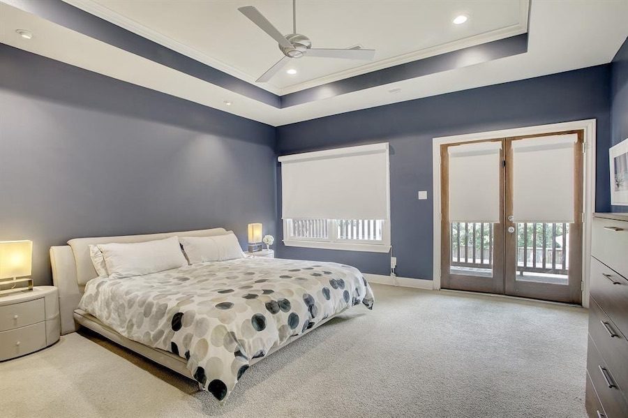 purple walls in master bedroom with white roller shades in Houston TX