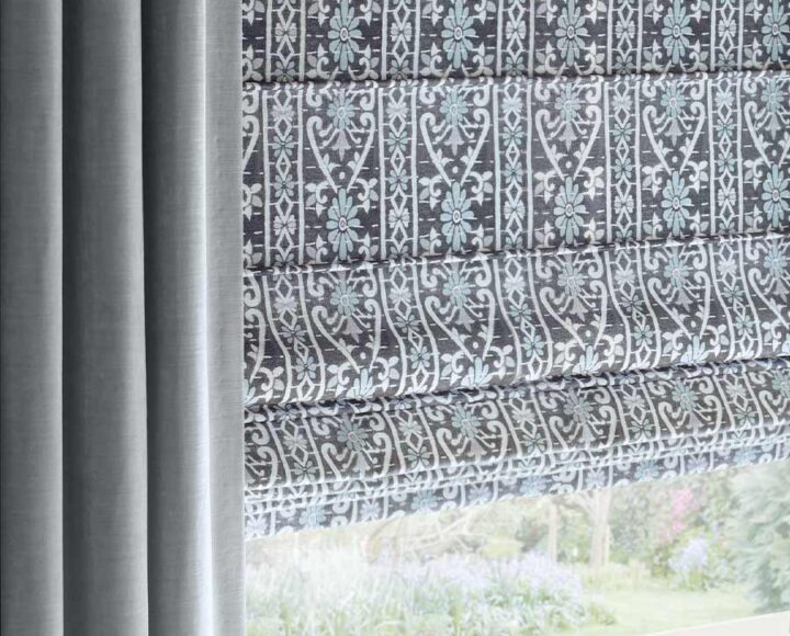 plush gray custom draperies framing blue, gray and white patterned roman shades