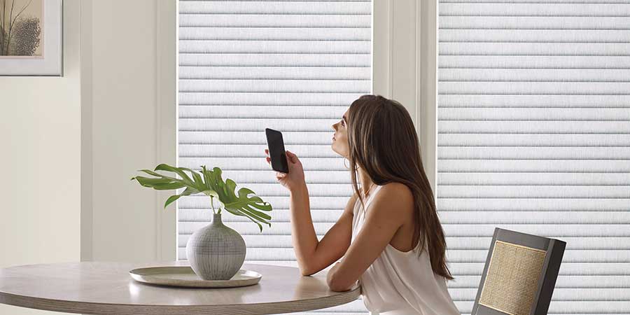 automatic white window coverings being operated with smart phone in kitchen