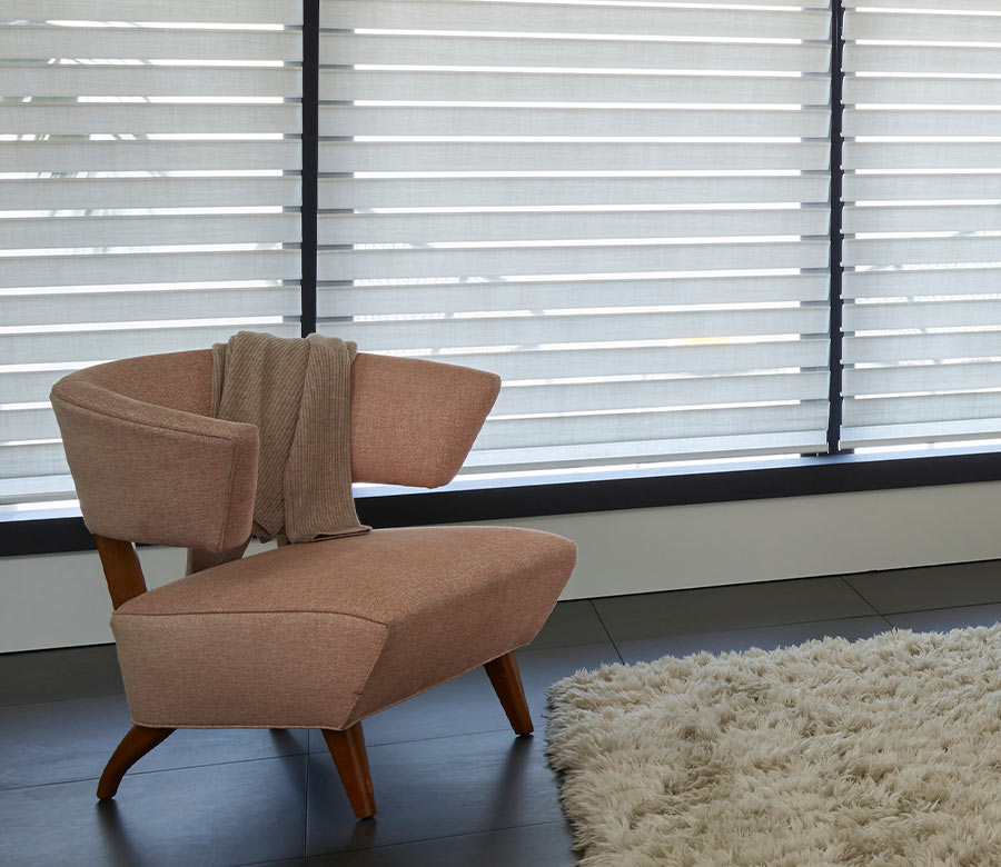 Silhouette light-filtering shades on wide windows, casting soft natural light over a contemporary chair and textured rug