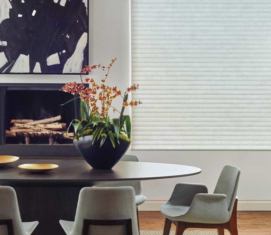 Dining area featuring a closed white honeycomb shade and round table