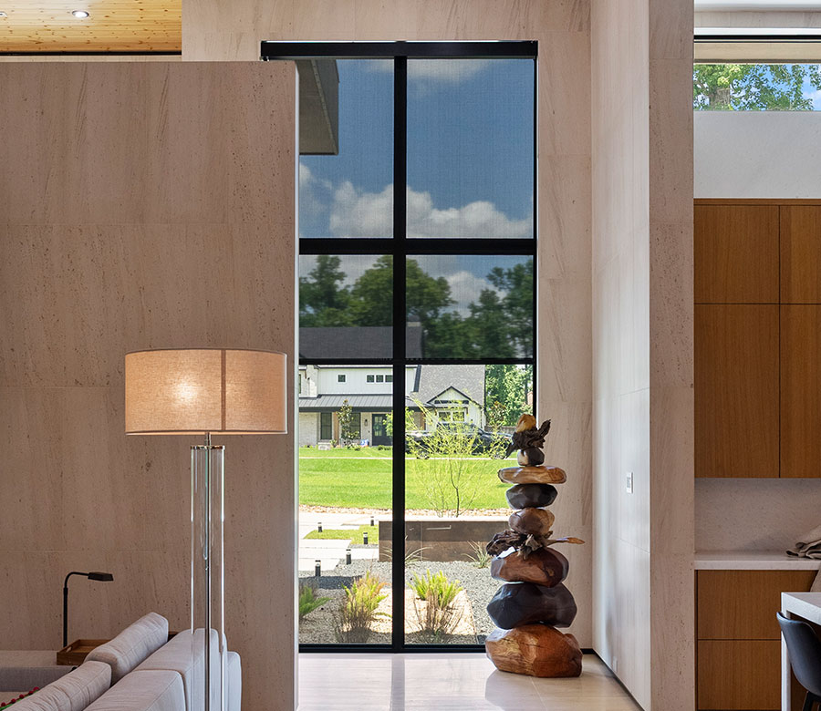 Black solar shades reducing glare across floor-to-ceiling windows in a Galveston home