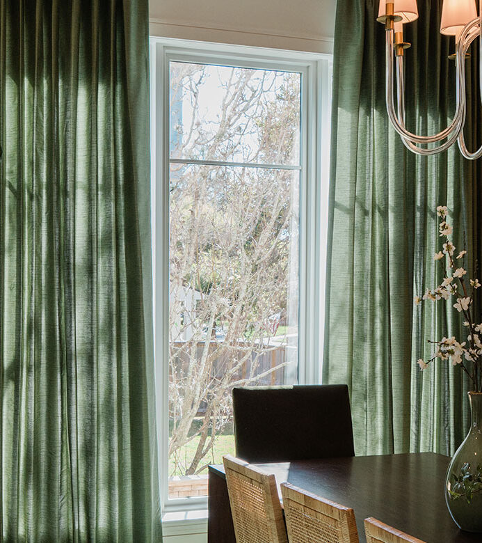 Green pinch pleat drapery framing dining room windows