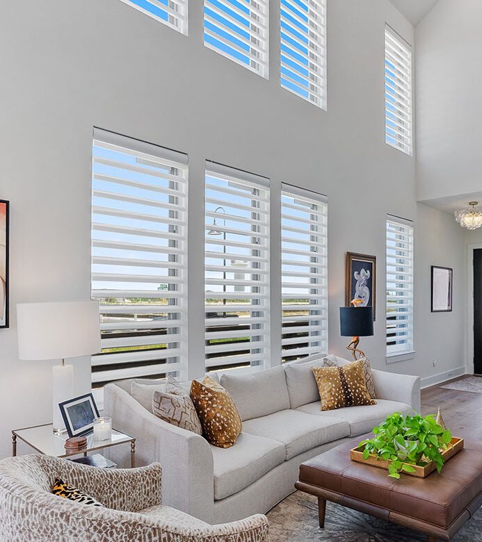 White motorized Pirouette® shades on two-story living room windows in a Cypress home