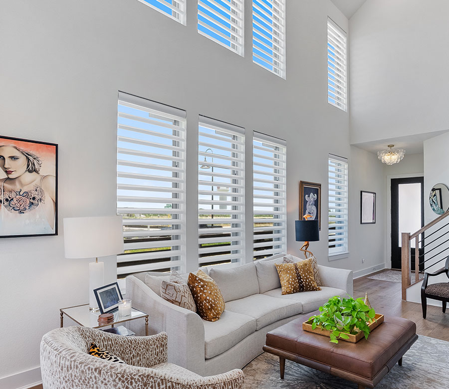 White motorized Pirouette® shades on two-story living room windows in a Cypress home